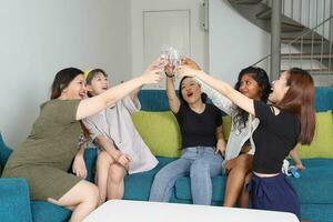 Jeune asiatique femme groupe parler potins bavarder chanter boisson à votre santé fête amusement prendre plaisir émotion sur bleu vivant pièce canapé photo