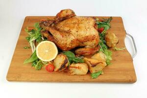 entier rôti grillé poulet la volaille oiseau avec cuit Patate légume salade tomate citron sur en bois Coupe planche blanc Contexte photo