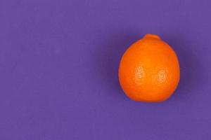 mandarine orange sur fond de papier violet photo
