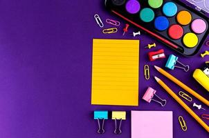fournitures de bureau scolaire sur un bureau de fond violet photo
