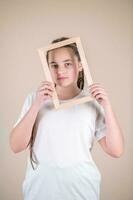 portrait de une mignonne peu fille en portant une image Cadre. studio coup photo