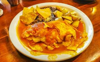 Oeufs d'omelette mexicaine haricots noirs pommes de terre nachos sur plaque blanche. photo