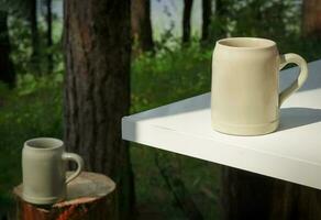 deux gros céramique des tasses permanent sur table et souche dans en plein air dans forêt la nature avec visible arbre les troncs et l'eau sur le Contexte photo