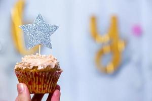 main de fille tient le cupcake aux canneberges avec étoile à paillettes argentées photo
