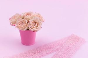 un bouquet de belles roses se dresse dans un petit seau sur un ruban de dentelle photo