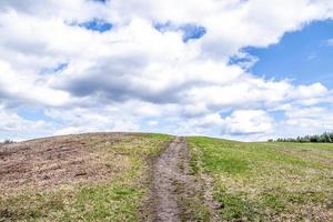 colline herbeuse verte devant un ciel nuageux photo