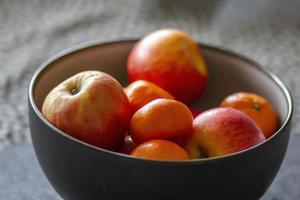 Bol d'oranges et de pommes biologiques fraîches sur une table photo