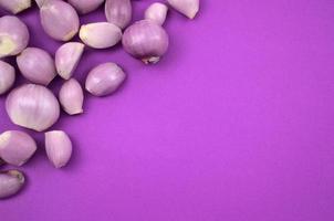 Oignons frais à éplucher à plat sur fond violet photo