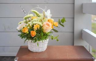 Un beau bouquet de fleurs fraîches dans un panier sur une valise vintage sur un fond de mur gris photo