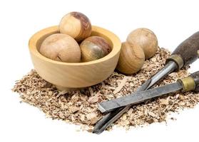 La main a tourné des boules de bois dans un bol décoré de sciure de bois et outil isolé sur blanc photo