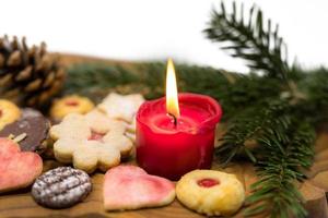 Bougie rouge allumée se dresse entre les biscuits de Noël décorés sur une planche de bois