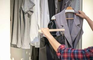 femelle main choisir vêtements pour vérifié modèle pantalon sur le grille dans tissu magasin à une département magasin. vérifier prix, rabais, et promotion de Vêtements des produits. photo