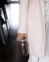 femme tenant un pot de grains de café