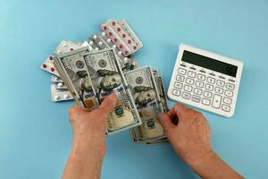 mains de un personnes âgées femme compte argent suivant à une calculatrice et packs de médicaments photo