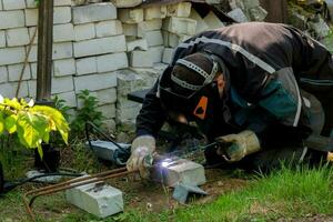 homme Faire soudage tandis que bâtiment le sien maison photo