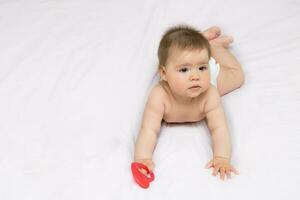 charmant mignonne bébé fille mensonges sur sa ventre sur une lumière Contexte avec copie espace photo