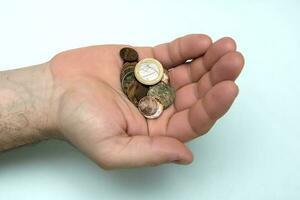 dans une homme main une poignée de rouillé pièces de monnaie avec une pièce de monnaie de 1 euro photo