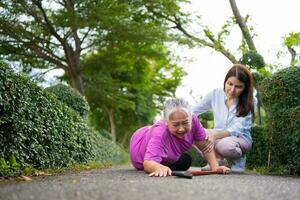 une femme âgée asiatique est tombée sur le sol couché parce que la faiblesse et la faiblesse des membres et les pleurs de douleur sous forme d'accident et sa fille sont venues aider à soutenir. concept d'assurance vieillesse et de soins de santé photo