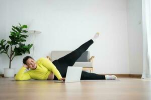 asiatique en surpoids femme Faire élongation exercice à Accueil sur aptitude tapis. Accueil activité entraînement, en ligne aptitude classe. élongation formation faire des exercices sur yoga tapis à Accueil pour bien santé et corps forme. photo