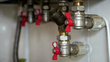 caché l'eau robinets pour de liaison une gaz Chaudière sur une carrelé mur. plomberie Connexions pour une national double circuit gaz Chaudière. tuyaux de le chauffage système. installation une gaz Chaudière avec rouge robinets. photo