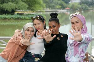 groupe de femme malais chinois Indien asiatique malais Extérieur vert parc Lac la nature parler à le main Arrêtez geste photo