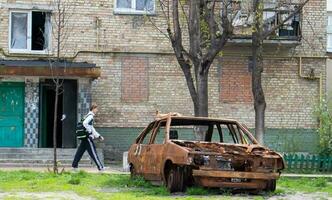 une cassé voiture, coup par artillerie, des stands dans le Cour de une à plusieurs étages Résidentiel bâtiment. guerre entre Russie et Ukraine. le débris de un abandonné auto. Ukraine, kyiv - mai 06, 2023. photo