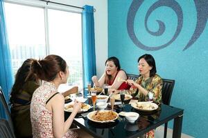 Jeune sud-est asiatique femme groupe parler célébrer en mangeant profiter nourriture riz curry nouille poulet boisson à votre santé sur à manger table photo