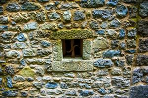 petite fenêtre carrée sur le mur de pierre