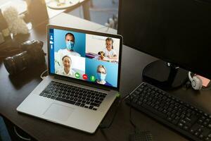 fermer de médecin ayant vidéo conférence sur portable à en bois bureau photo