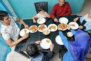 groupe de sud-est asiatique adulte enfant fille Masculin femelle en mangeant le déjeuner à à manger table mis à la porte poulet. elles ou ils sont autistique vers le bas syndrome adhd paralysé fauteuil roulant photo