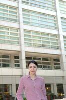 Jeune Sud est asiatique milieu femme affaires collègue dans de face de une grand bâtiment Regardez vers l'avant à caméra photo