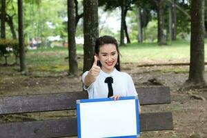 Jeune asiatique chinois femme Extérieur parc Campus livre fichier dossier portable ordinateur téléphone asseoir supporter étude mêler photo