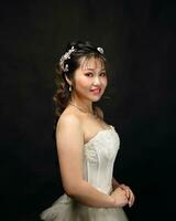 Jeune asiatique femme dans blanc robe cheveux couronne sur noir Contexte photo