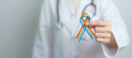 médecin avec lgbtq arc en ciel ruban pour soutien lesbienne, gay, bisexuel, transgenres et queer communauté et content fierté mois concept photo