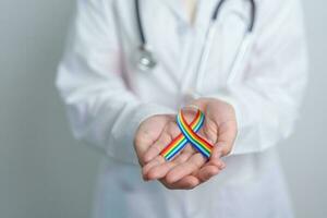 médecin avec lgbtq arc en ciel ruban pour soutien lesbienne, gay, bisexuel, transgenres et queer communauté et content fierté mois concept photo