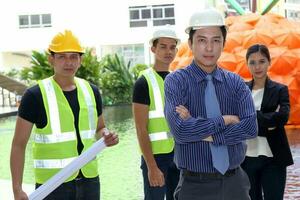 Sud est asiatique Jeune malais chinois homme femme sécurité casque gilet vêtements de cérémonie supporter à construction site plan plan presse-papiers Regardez à caméra photo