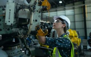 une femelle ingénieur installe une programme sur une la robotique bras dans une robot entrepôt. et tester le opération avant Envoi en cours le machine à le client. photo