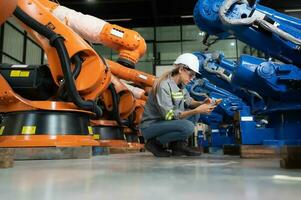 dans le des robots entrepôt, une femelle ingénieur inspecte le électrique système de chaque la robotique bras, avant livrer à le client. photo