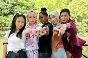 groupe de cinq femme copains malais chinois Indien asiatique malais Extérieur vert parc Lac la nature montrer du doigt doigt à vous vers caméra photo