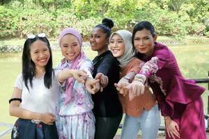 groupe de cinq femme copains malais chinois Indien asiatique malais Extérieur vert parc Lac la nature montrer du doigt doigt à vous vers caméra photo