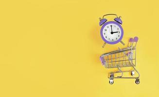 Chariot de supermarché et réveil violet sur fond jaune avec espace copie acheter du temps occupé concept photo
