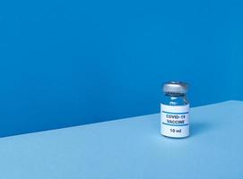 Flacon de médicament avec vaccin covid 19 sur fond bleu avec skyline tendance inclinée et espace de copie