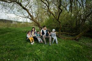 famille avec Trois des gamins séance sur chaises à printemps forêt. photo