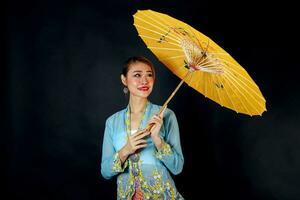 asiatique femme dans tractionnel kebaya porter parapluie sur noir Contexte photo