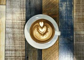 chaud café latté dans coloré tasse et soucoupe sur rustique en bois table photo