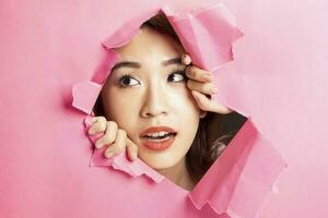 Jeune magnifique asiatique femme expression par déchiré papier trou photo
