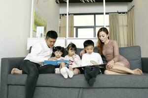 Parents enfant famille père mère fille fils asseoir sur canapé en train de lire l'écriture étude enseignement photo