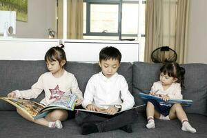 enfant famille père mère fille fils asseoir sur canapé en train de lire l'écriture étude enseignement photo