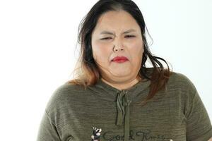 Jeune plus Taille Sud est asiatique femme pose visage expression émotion sur blanc Contexte dégoûté photo