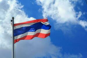 le thaïlandais drapeau cette est soufflé une façon par le vent avec le bleu ciel Contexte et des nuages dans le milieu de le chaud Soleil et fort vent. photo